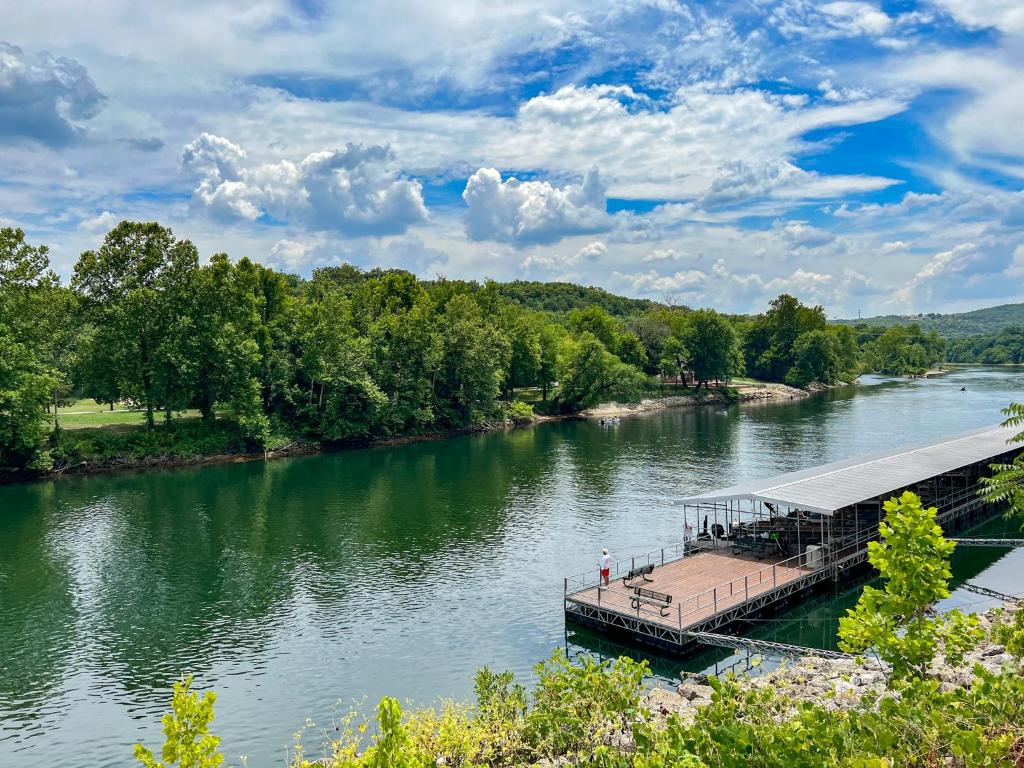 a dock on a river with trees in the background at Lake Front 2BR Walk-In with Large Deck - FREE TICKETS INCLUDED - 79-1 in Branson