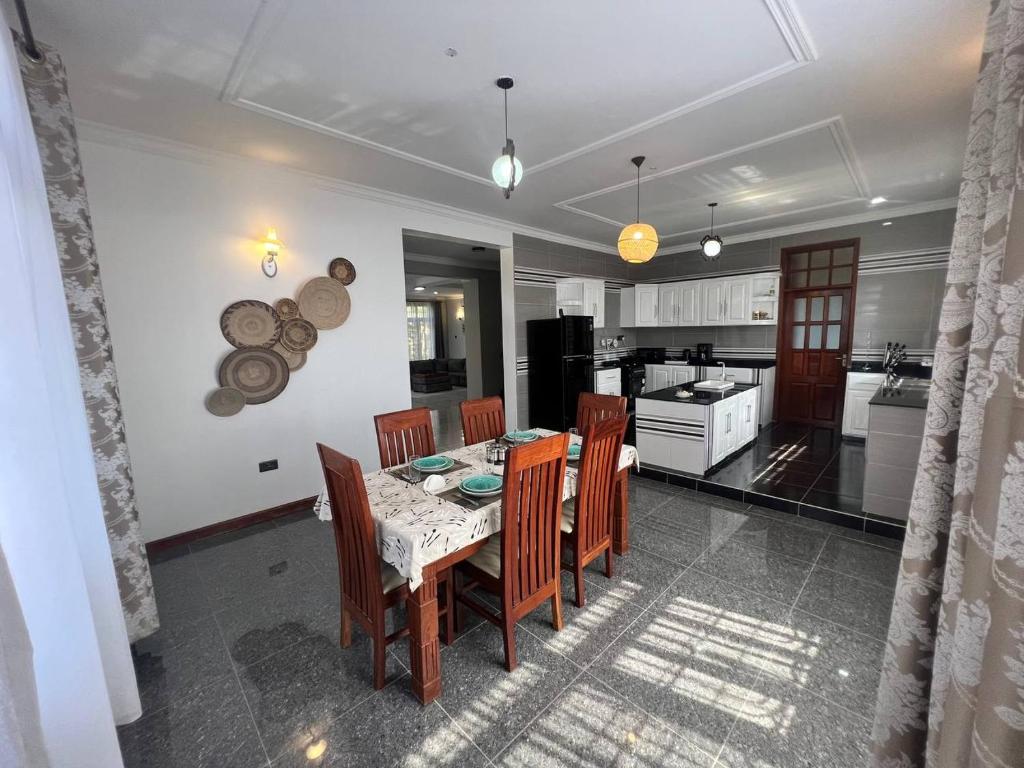 a dining room with a table and chairs and a kitchen at Lerai Homes in Arusha