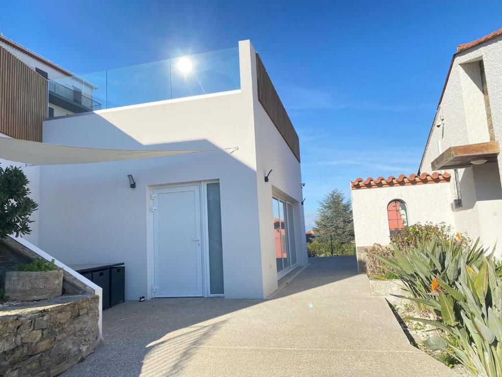 a white house with a door in a driveway at La Maison Du Belvedere in Saint-Cyprien