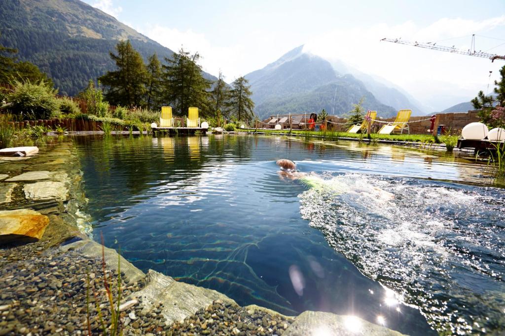ein Hund schwimmt in einem Wasser-Pool in der Unterkunft GRÜNER Alpengasthof inkl Summercard in Sölden