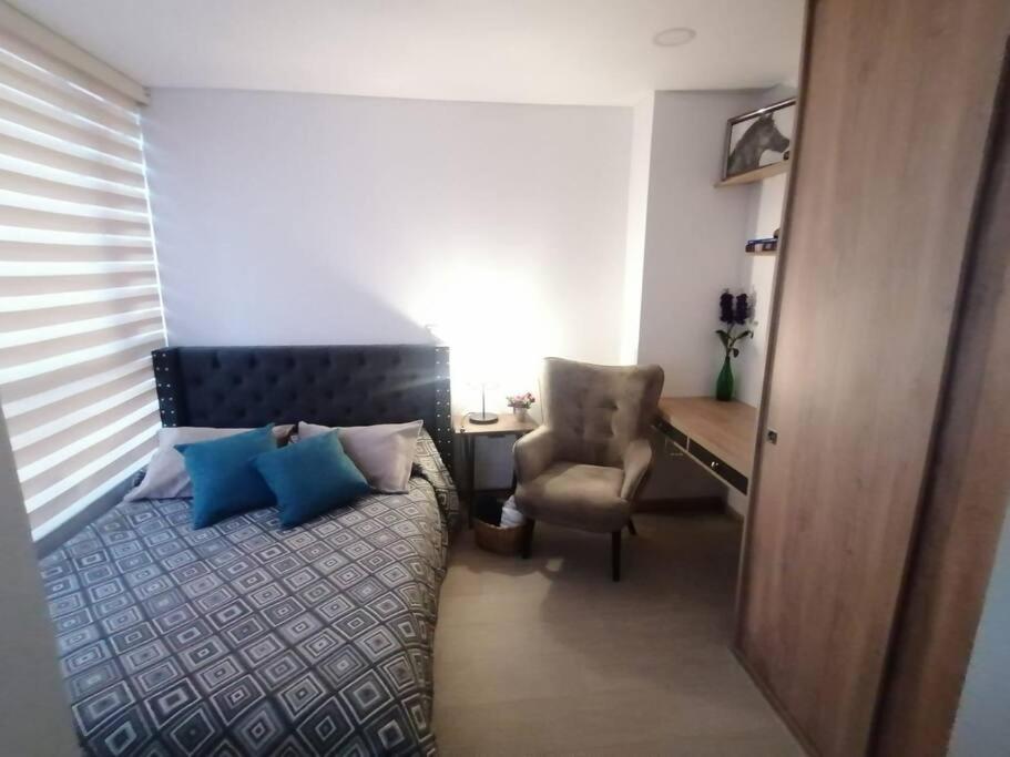 Un dormitorio con una cama con almohadas azules y una silla en Moderno Apartamento Chapinero Bogota, en Bogotá