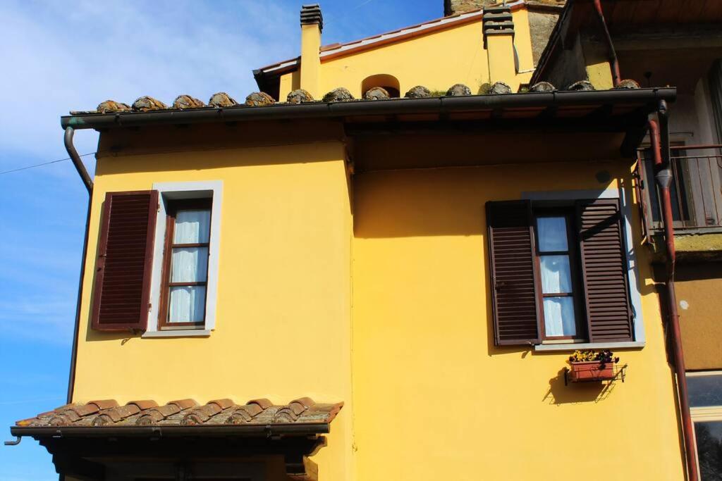 ein gelbes Gebäude mit zwei Fenstern und einem Dach in der Unterkunft affittacamere la torre in Tegoleto
