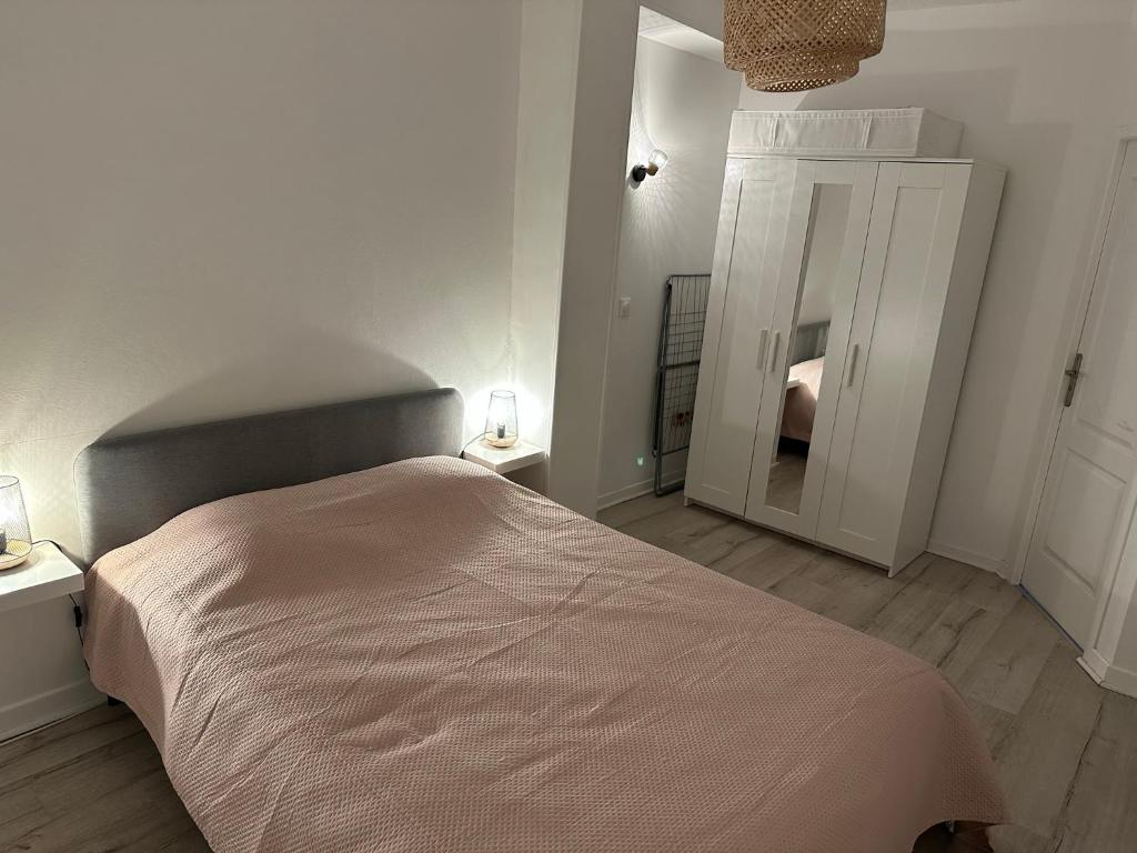 ein weißes Schlafzimmer mit einem Bett und zwei Lampen in der Unterkunft Appartement spacieux - proche centre et therme in Bagnères-de-Bigorre
