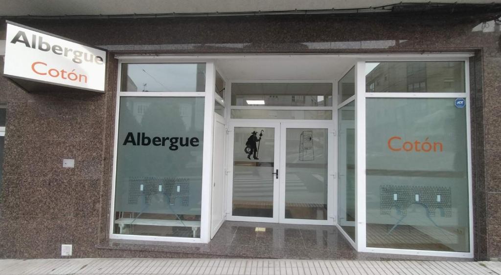 una tienda con puertas de cristal y una persona entrando en Albergue Cotón en Negreira