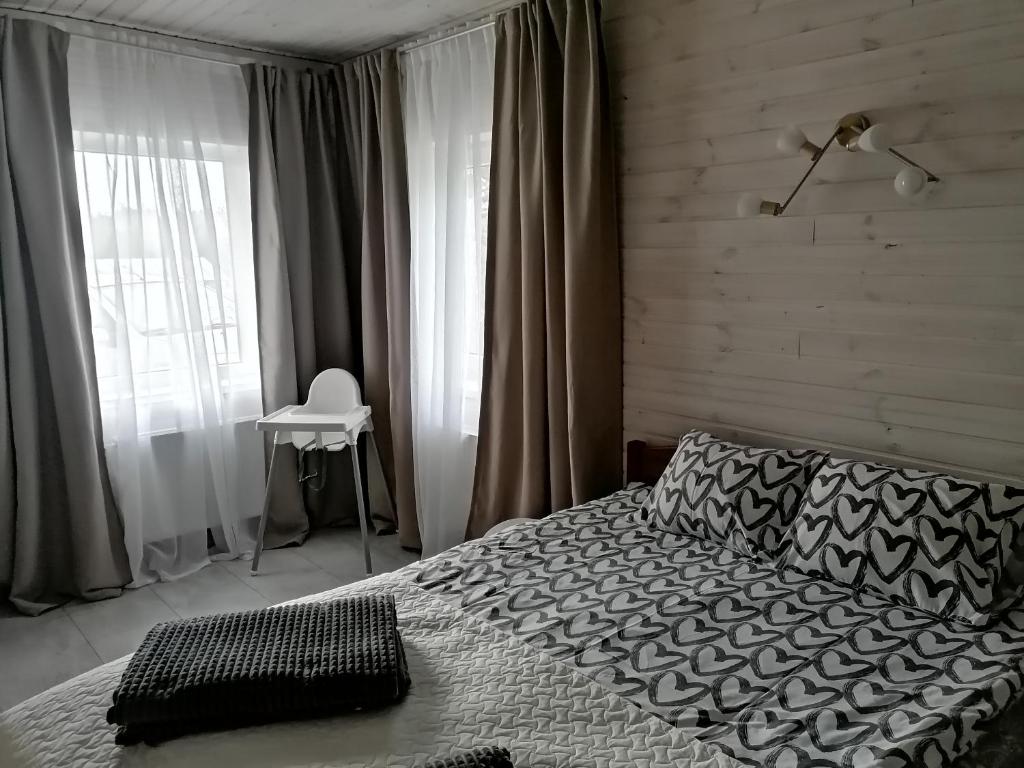 Schlafzimmer mit einem Bett und einem Fenster mit einem Stuhl in der Unterkunft FOREST LAKE in Kščava