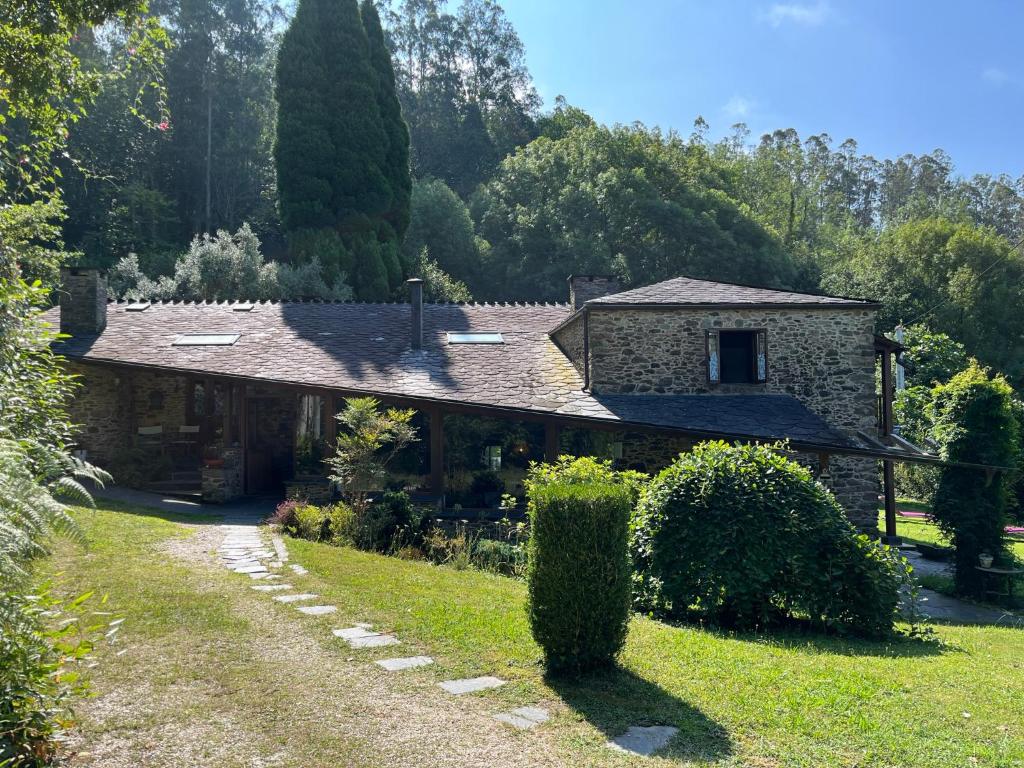 una casa de piedra en una colina con un camino que conduce a ella en Casa Rural O Vilar en Mera de arriba