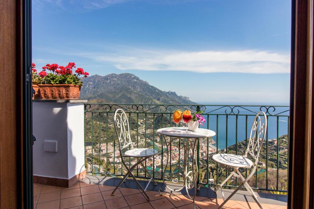 a balcony with two chairs and a table with flowers on it at Via Col Vento in Ravello
