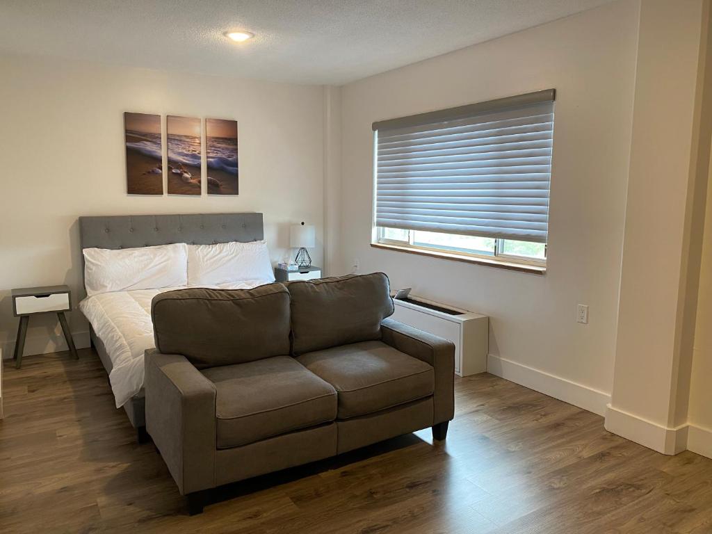 a bedroom with a couch and a bed and a window at Lovely Micro Studio Apartment in Downtown Gadsden in Gadsden