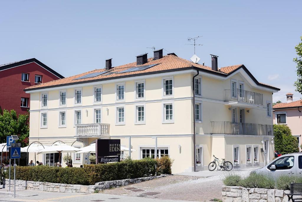 a large white building with a car parked in front of it at Hotel Eden in Sistiana