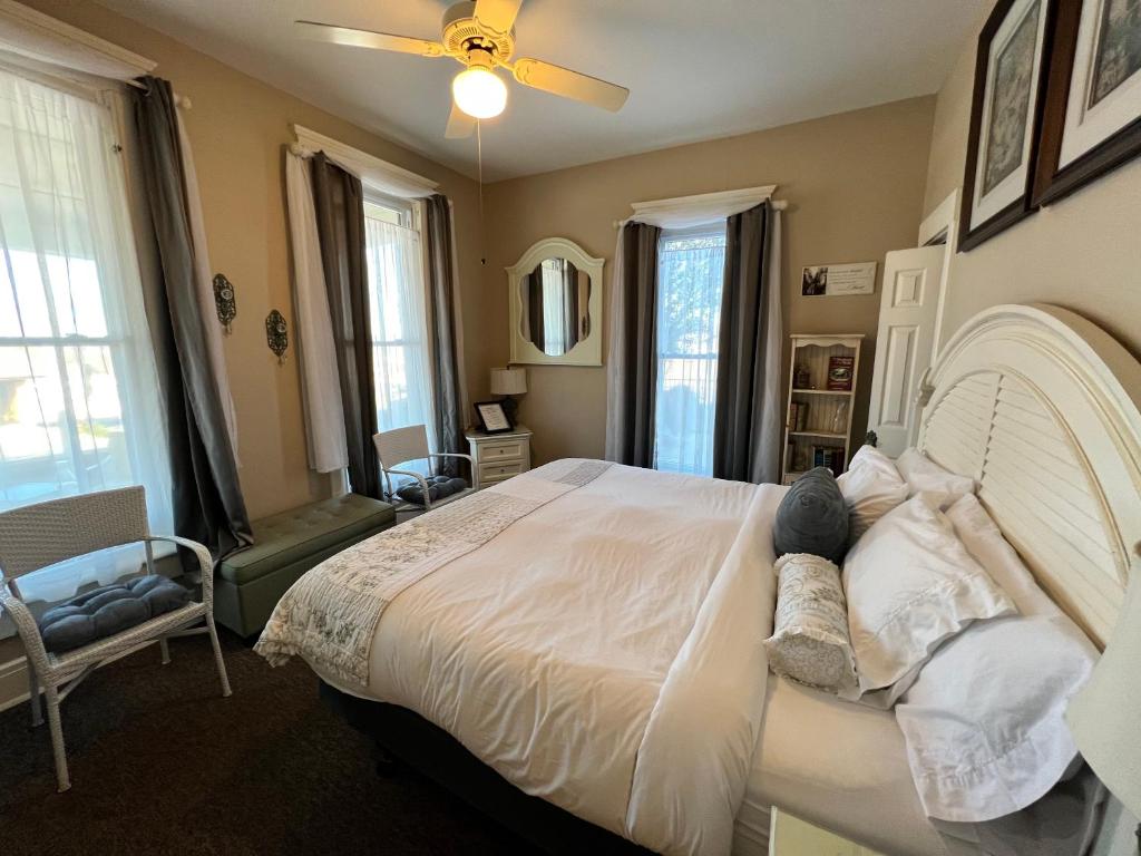 a bedroom with a large white bed with a ceiling fan at Historic Branson Hotel - Quiet Quilt Room with King Bed - Downtown - FREE TICKETS INCLUDED in Branson