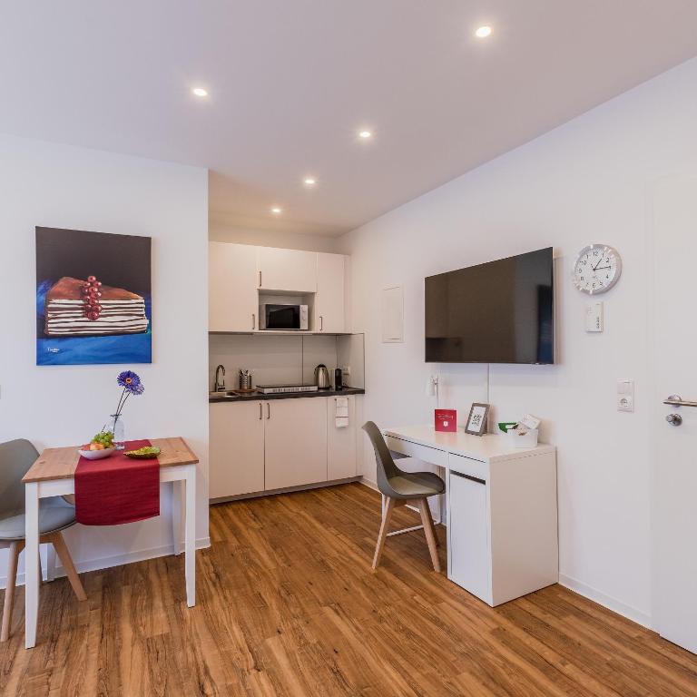 a kitchen and dining room with a table and a desk at IMMOCITY Apartments in Griesheim