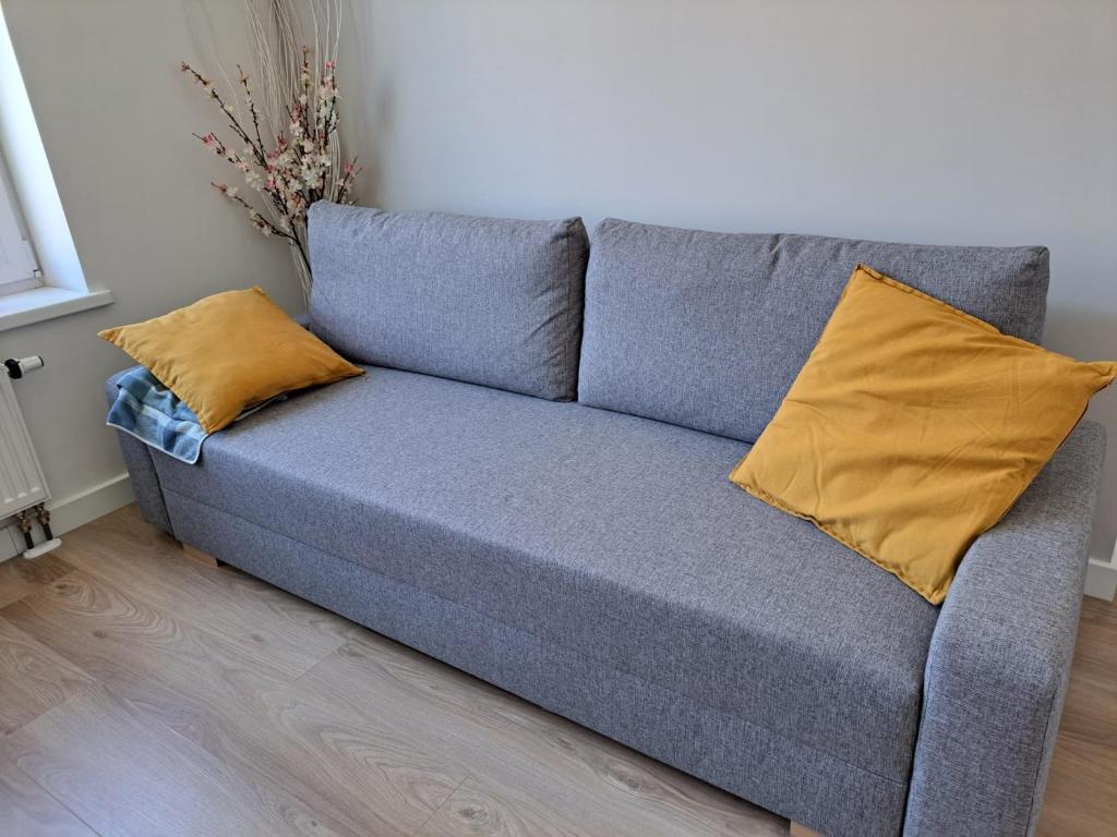 a gray couch with two yellow pillows in a room at Oak apartment in Riga