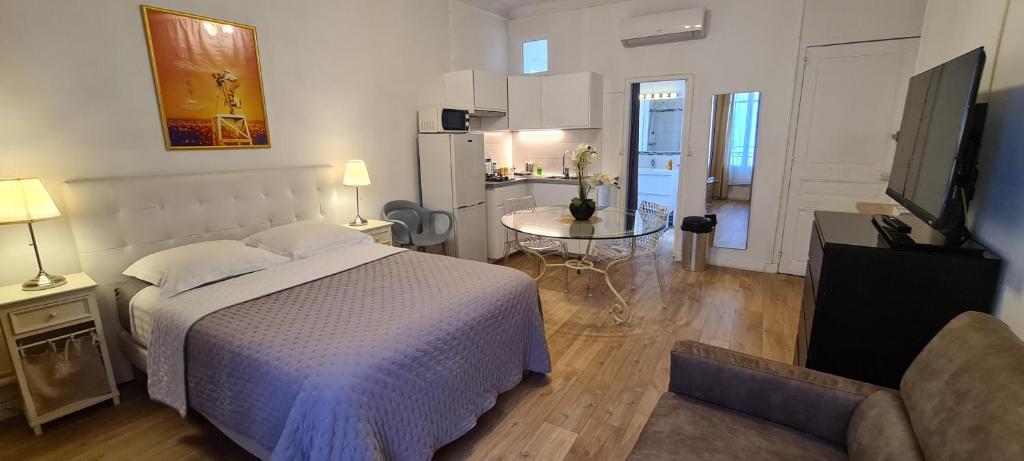 a bedroom with a bed and a table and a kitchen at SeaYouSoon Inn Cannes - Studios in Cannes