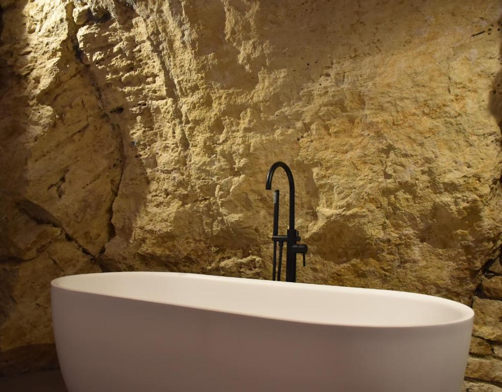 y baño con bañera y pared de piedra. en Casa Cicetta en San Marino