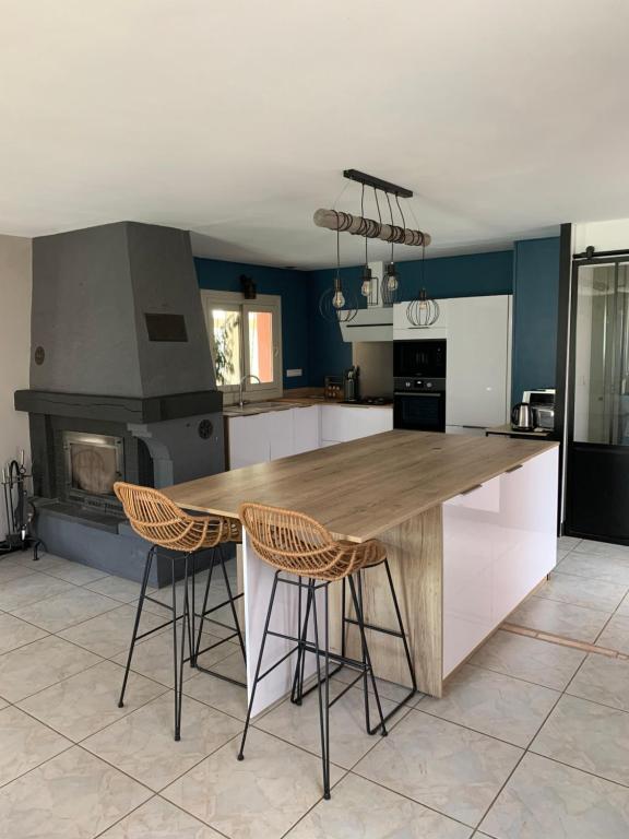 - une cuisine avec un comptoir en bois et deux tabourets de bar dans l'établissement Lapeyre, à Lignan-de-Bazas