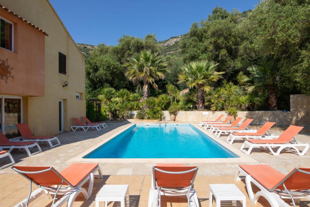 een zwembad met ligstoelen en een resort bij Residence Helios in Cargèse