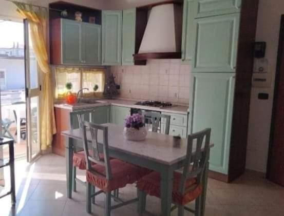 eine Küche mit einem Tisch mit Stühlen und einem Herd in der Unterkunft Appartamenti & Camere TRA SCILLA e TROPEA in San Ferdinando