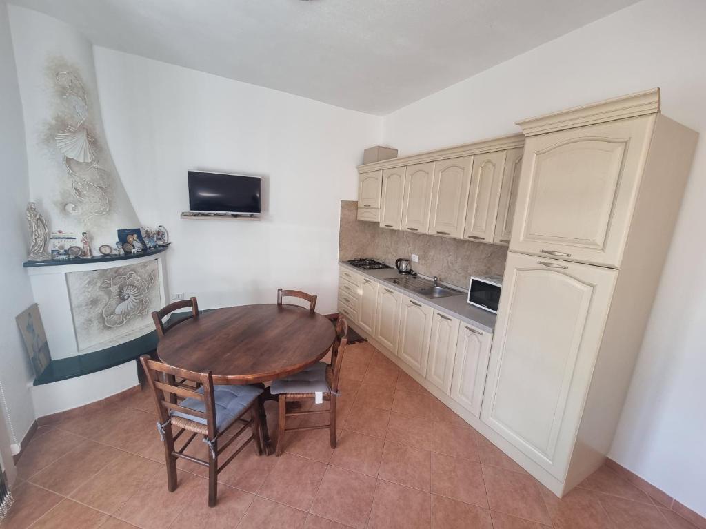 a kitchen with a wooden table and a refrigerator at Appartamento Monte Mare Arzachena in Arzachena