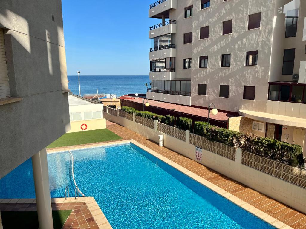 una piscina al lado de un edificio con el océano en Apartment on the beach with parking and pool, en Calpe