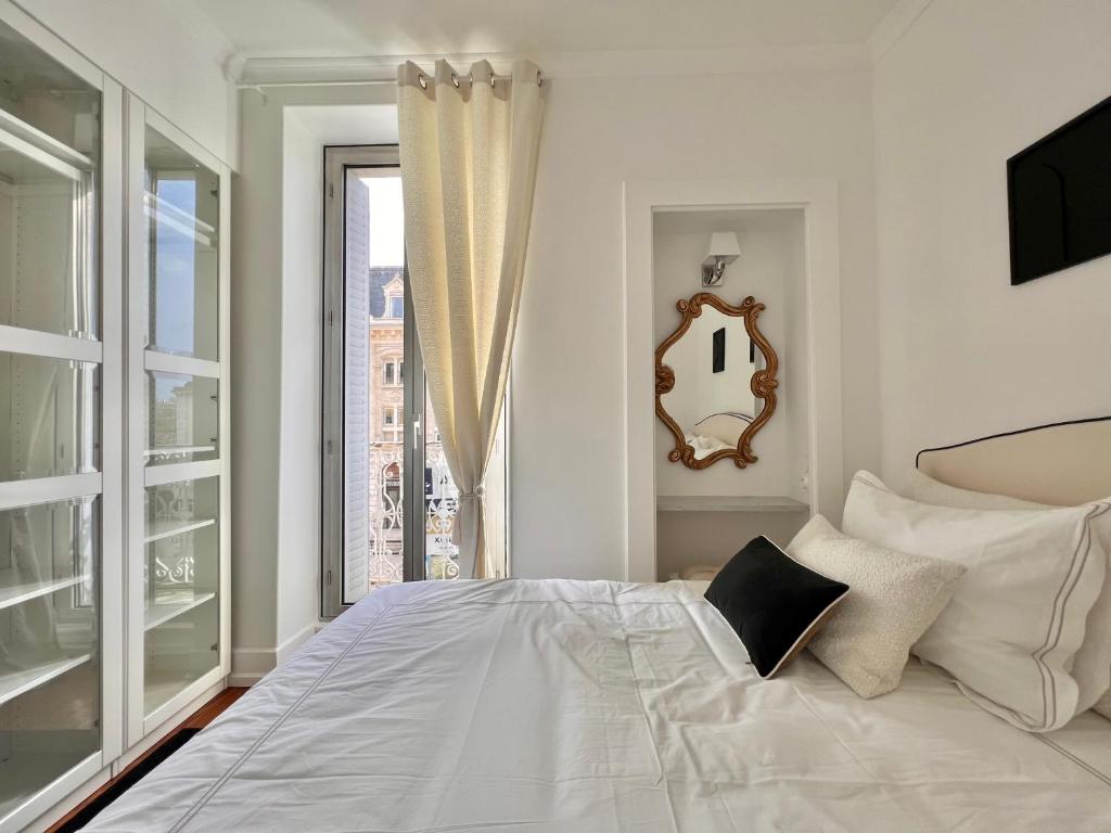 a white bedroom with a large bed and a window at Le Dijontissime Appartements haut de Gamme Dijon centre in Dijon