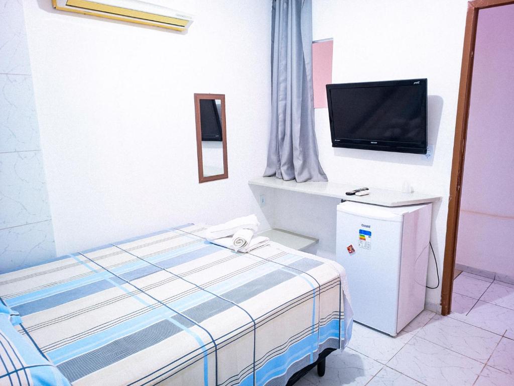a bedroom with a bed and a flat screen tv at Pousada Tô Em Casa! in João Pessoa