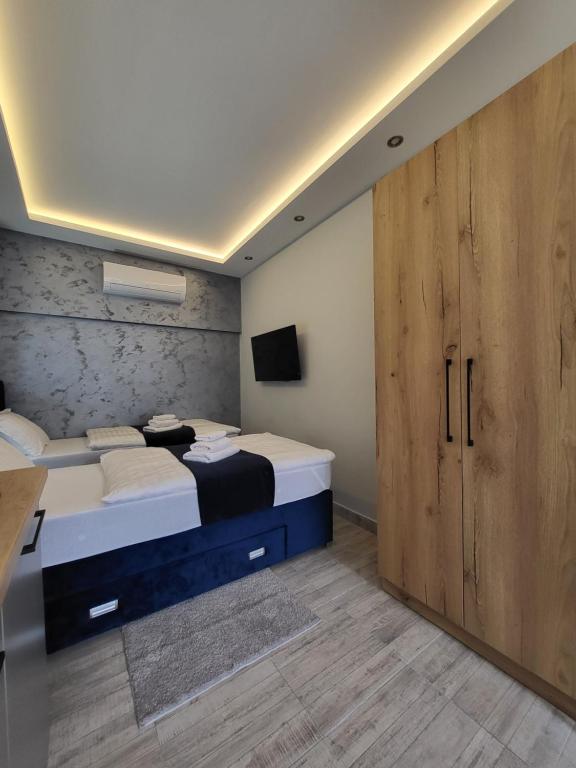 a bedroom with two beds and a large wooden door at Duga Apartmani 3 in Subotica