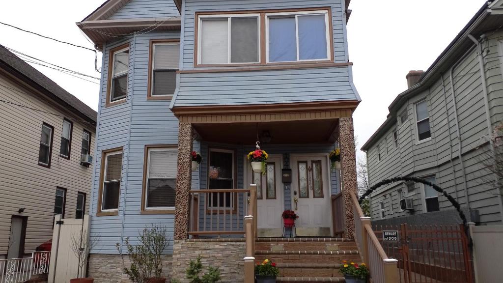 a blue house with a front porch with a door at HOVA HOUSE NORTH in Elizabeth