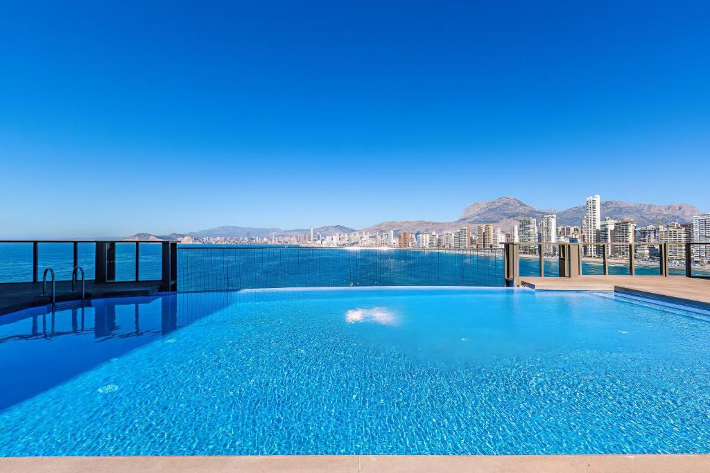 a large swimming pool with a view of the water at GEMELOS Levante beach apartments in Benidorm