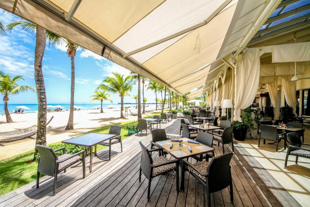 un patio esterno con tavoli, sedie e spiaggia di Courtyard by Marriott Isla Verde Beach Resort a San Juan