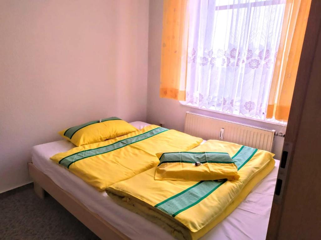 a bed with yellow sheets and pillows in a bedroom at Pension Stöß in Falkenstein