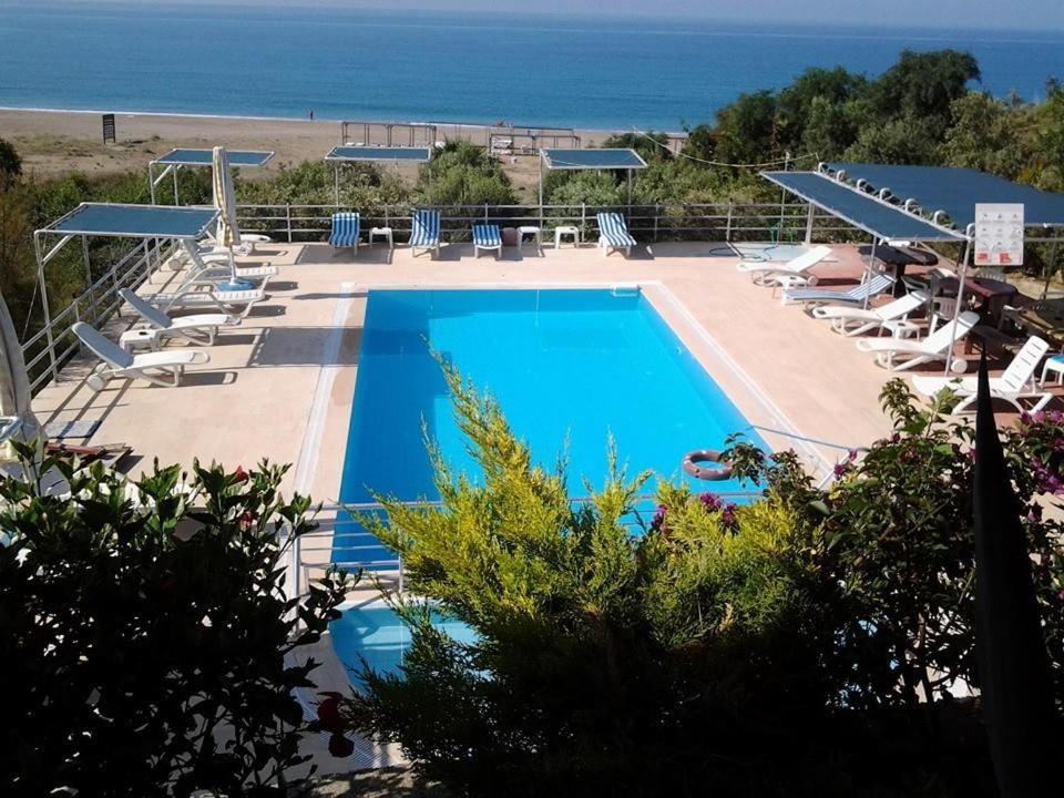 a large swimming pool with lounge chairs and the beach at Hotel Schönberg in Kızılot