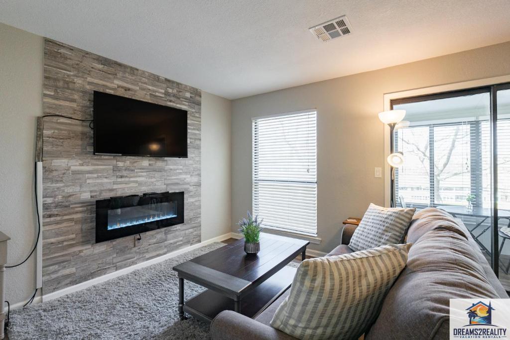 a living room with a couch and a tv on a brick wall at 1BR Walk-In Condo at Pointe Royal - 2 Pools - FREE ATTRACTIONS TICKETS INCLUDED -PR40-9 in Branson