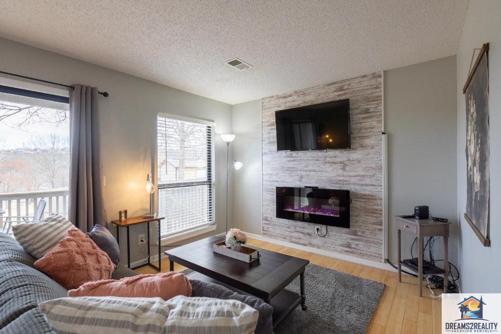 a living room with a couch and a tv on a brick wall at 1BR Walk-In Condo at Pointe Royal - 2 Pools - FREE ATTRACTION TICKETS INCLUDED -PR42-16 in Branson