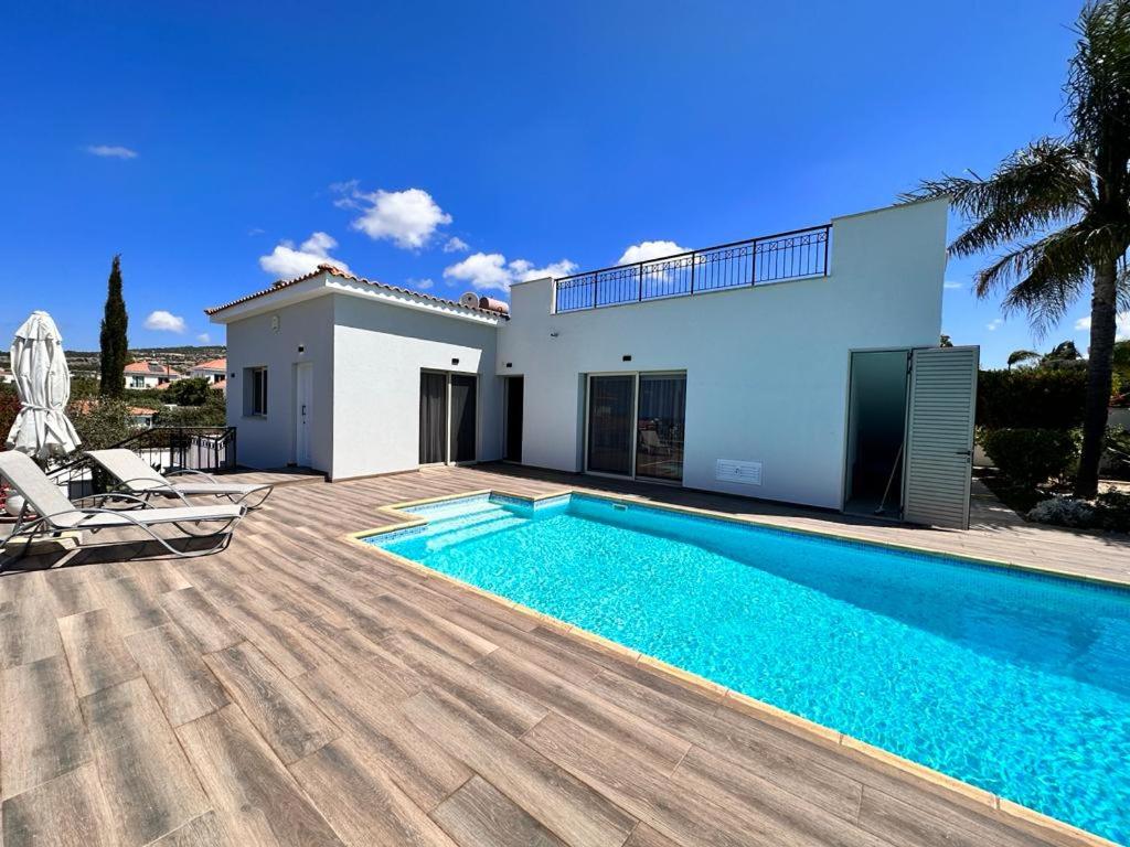 a villa with a swimming pool in front of a house at New Heaven in Sea Caves in Peyia