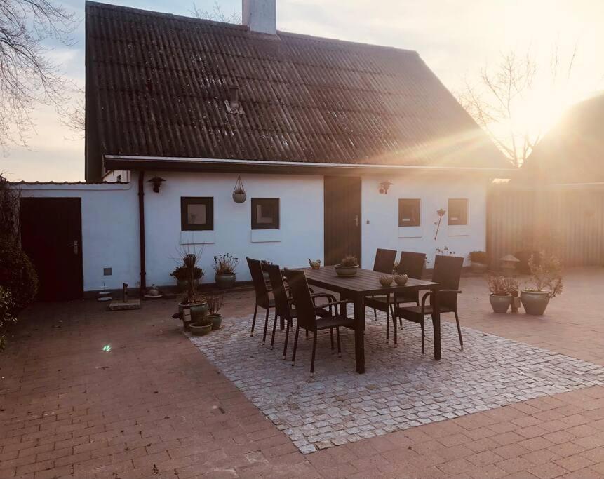 a patio with a table and chairs in front of a house at Hus på 100 m2 ved skov in Hårlev