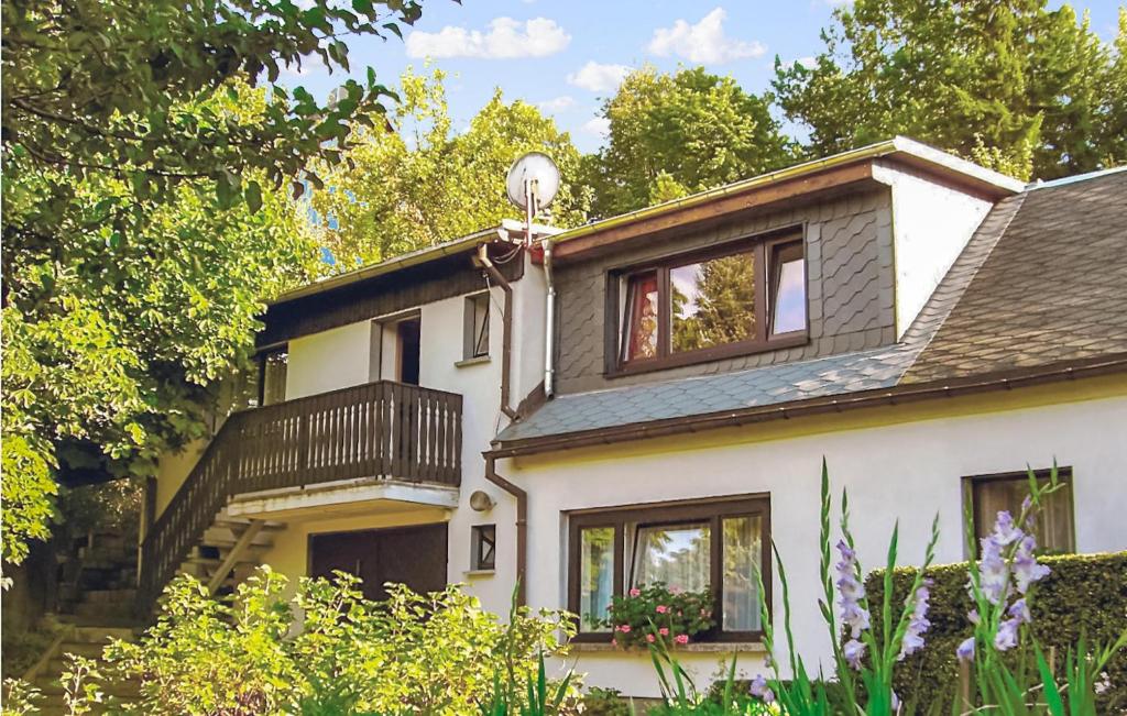 ein weißes Haus mit einem Balkon und Bäumen in der Unterkunft Ferienhaus Hauptstr. X in Ehrenberg