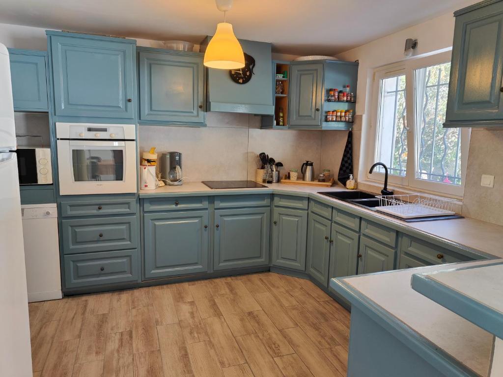 Il comprend une cuisine avec des placards bleus et du parquet. dans l'établissement Etoile de Mer - Appt 3 ch 2 sdb à 150m d'une plage de sable fin hyper équipé & Wifi, à Saint-Mandrier-sur-Mer