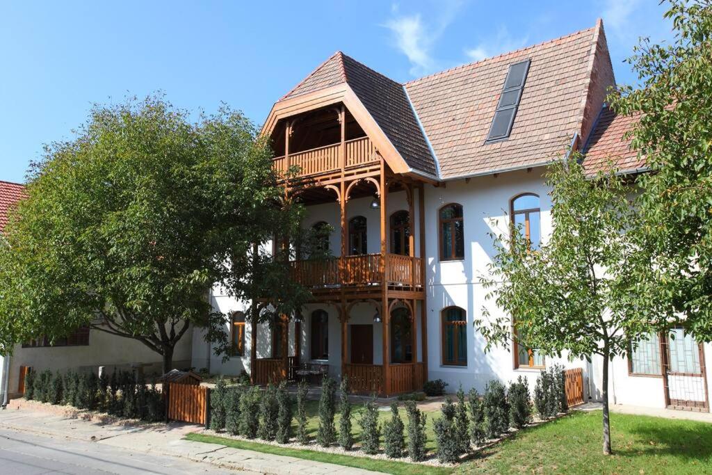 Una gran casa blanca con una terraza de madera. en Swiss villa in the Danube Bend, en Nagymaros