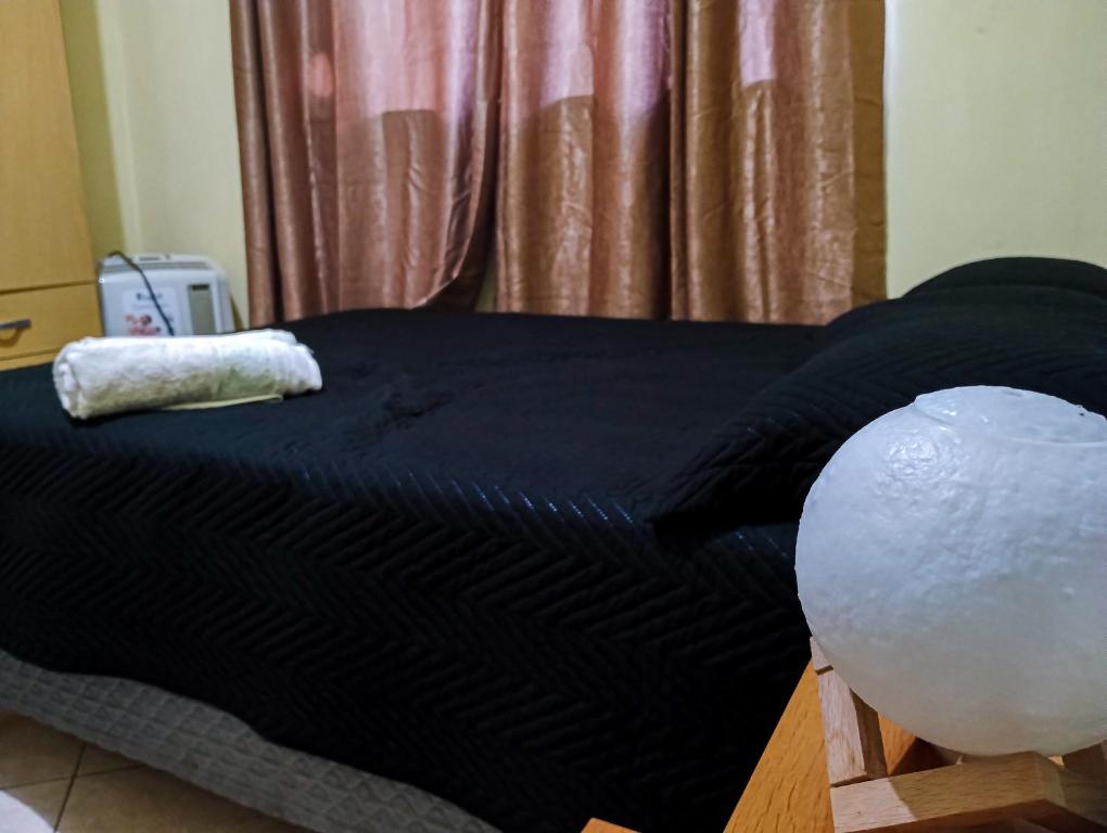 a bed with a black comforter in a room at Quarto Aconchegante Completo in Cruzeiro
