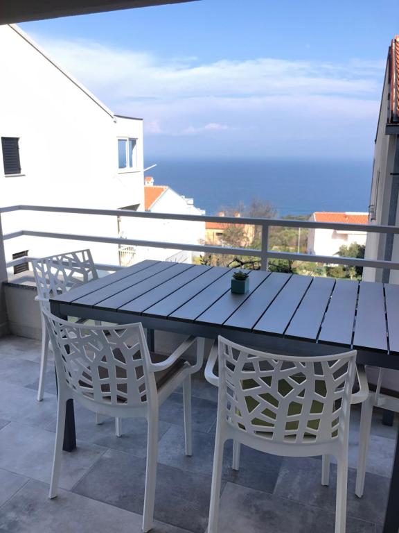 Apartment Sušanj Ravni with sea view في رافني: طاولة زرقاء وكراسي على شرفة مع المحيط