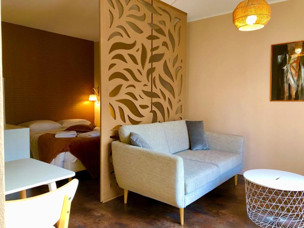 a hotel room with a couch and a bed at Charmant Studio à 2 pas de la gare in Lons-le-Saunier
