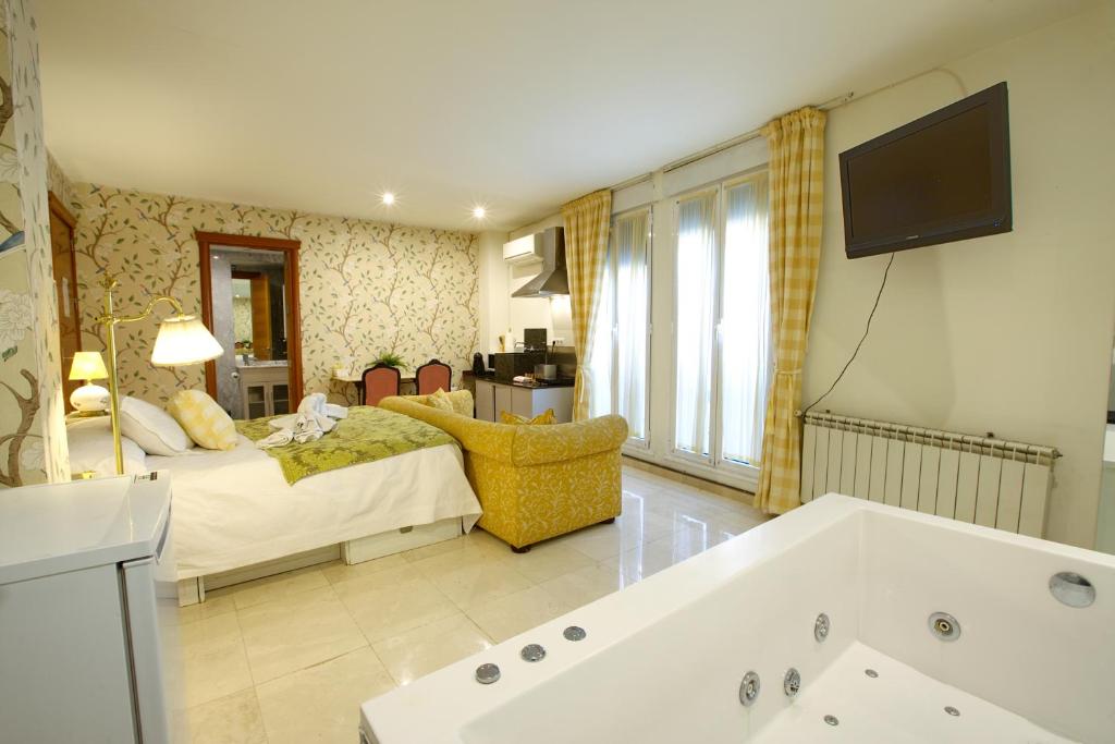 sala de estar con cama y bañera en Apartamentos Chvictoria, en Cuenca