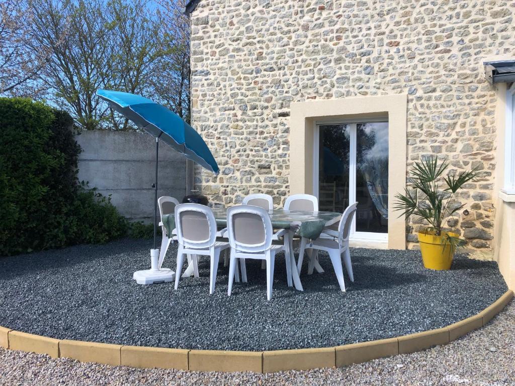 una mesa, sillas y una sombrilla en el patio en Gîte T'ché Dédée, en La Cambe