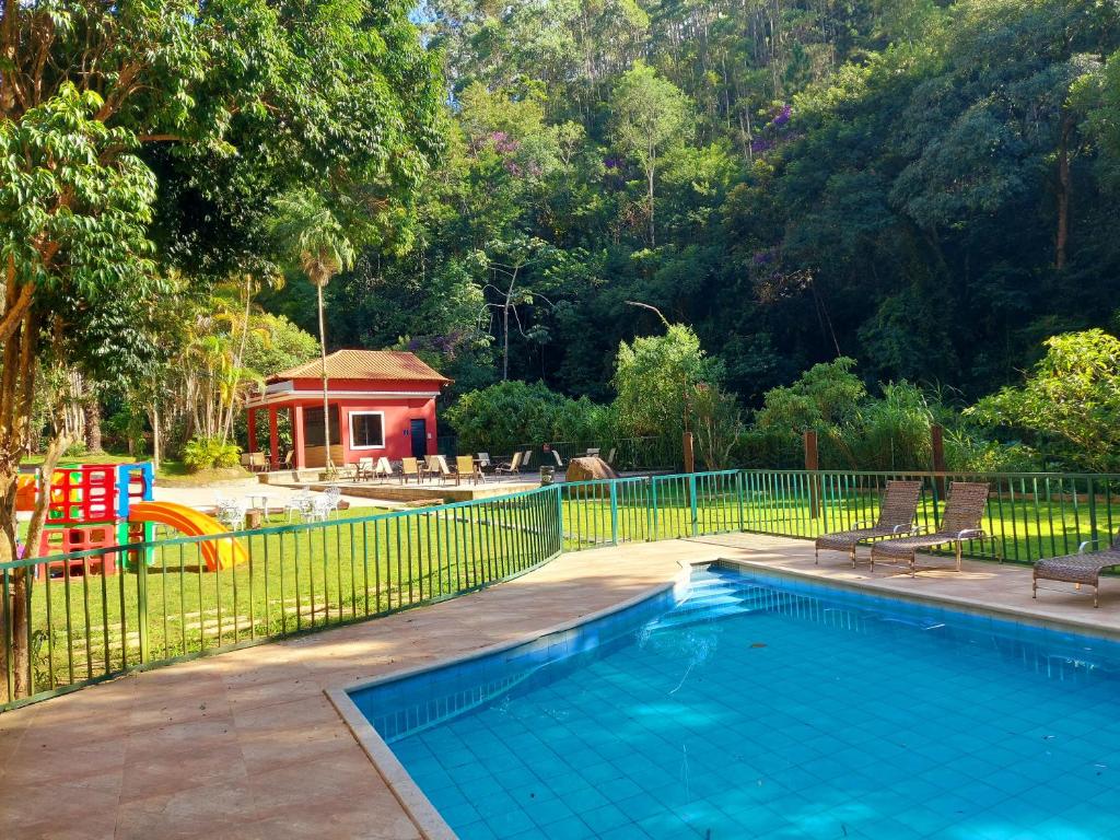 uma piscina ao lado de uma cerca com um parque infantil em Hotel Vila Suíça 1818 em Nova Friburgo
