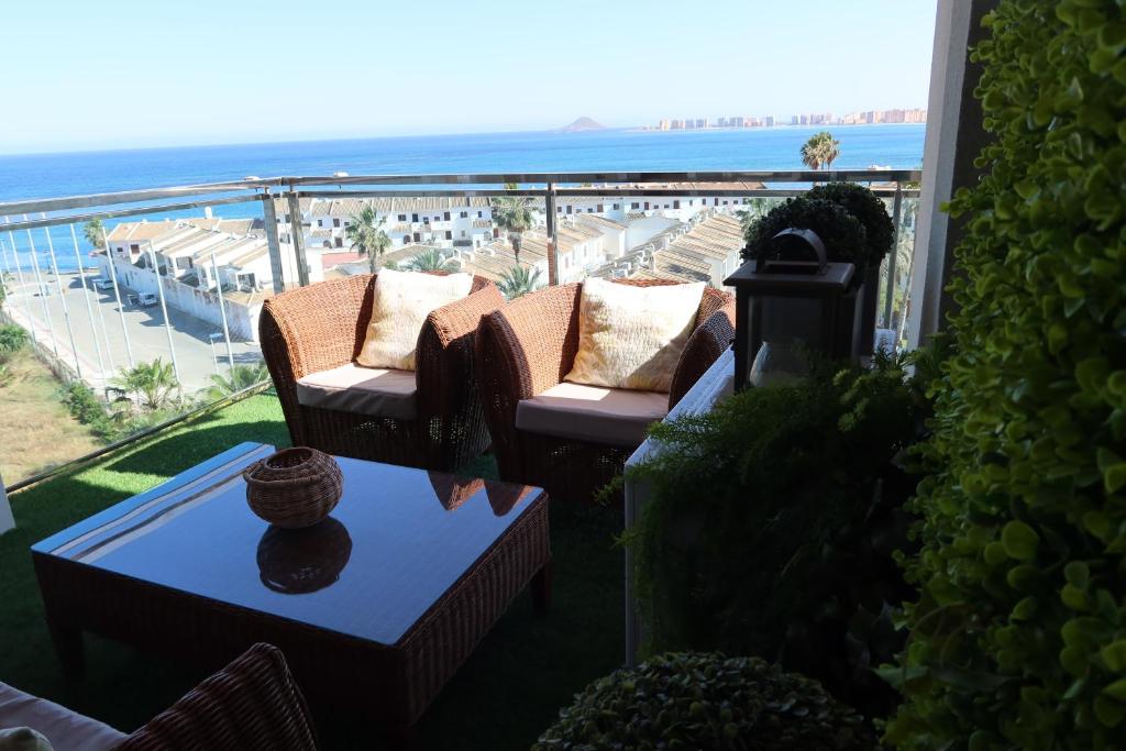 een balkon met 2 stoelen en een tafel met uitzicht op het strand bij EL REMANSO IV in La Manga del Mar Menor