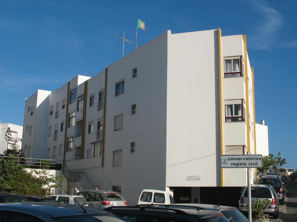 ein weißes Gebäude mit Autos auf einem Parkplatz in der Unterkunft APT Nazaré in Nazaré