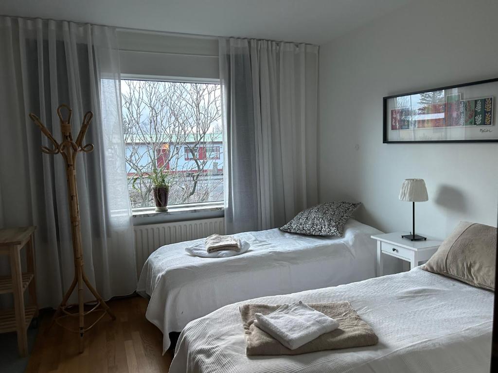 2 Betten in einem weißen Zimmer mit Fenster in der Unterkunft Art Guesthouse Olla in Selfoss