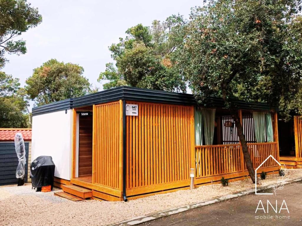 an orange and white shed with a fence at Ana Mobile Home - Kamp Soline - Biograd na Moru in Biograd na Moru