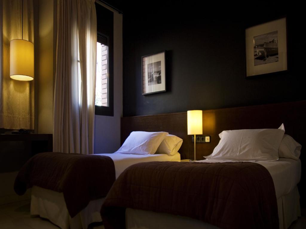 a hotel room with two beds and a window at Hostal Badaloní in Badalona