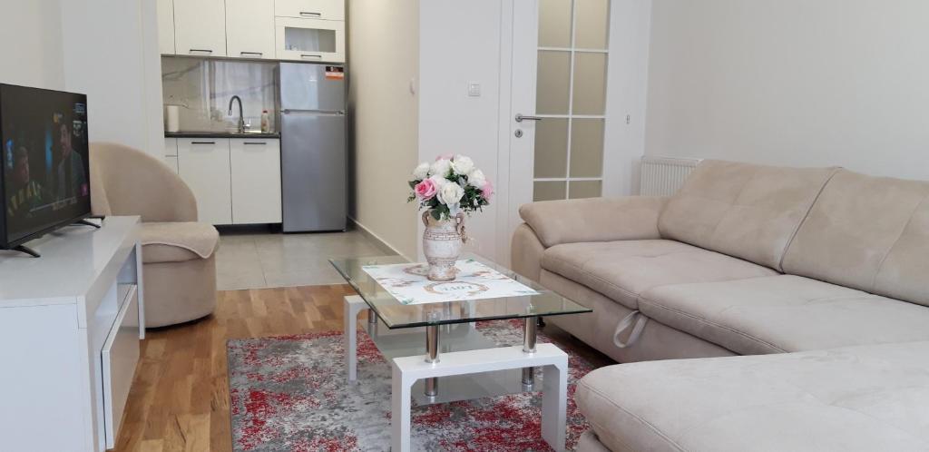 uma sala de estar com um sofá e uma mesa com flores em Apartman A1 em Bijeljina